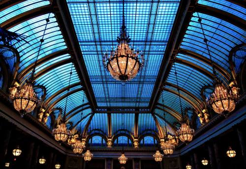 A grand ceiling with blue glass and ornate chandeliers, creating an elegant and luminous atmosphere.