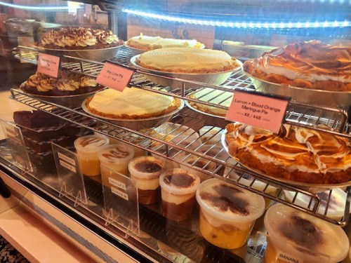A display case filled with various pies and desserts, including lemon pie, banana pudding, and almond tarts.
