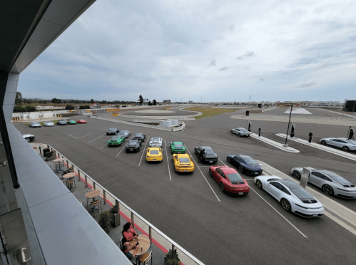 A lineup of colorful cars parked on a racetrack, with a cloudy sky in the background.