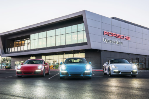 Three Porsche cars parked in front of the Porsche Experience Center, showcasing modern architecture and sleek design.