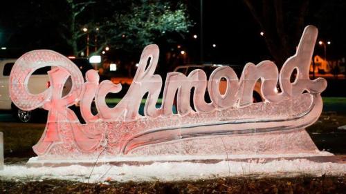 Illuminated ice sculpture of the word "Richmond" at night, with a decorative swirl design.
