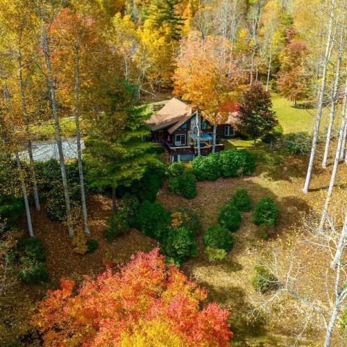 Aerial view of a cozy cabin surrounded by vibrant autumn foliage and colorful trees.