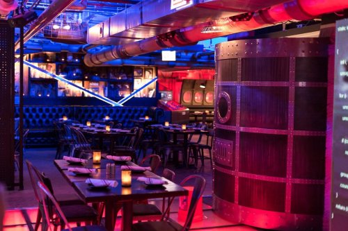 A vibrant restaurant interior with colorful lighting, modern decor, and tables set for dining.