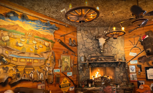 Cozy restaurant interior featuring a mural, stone fireplace, rustic decor, and a warm, inviting atmosphere.
