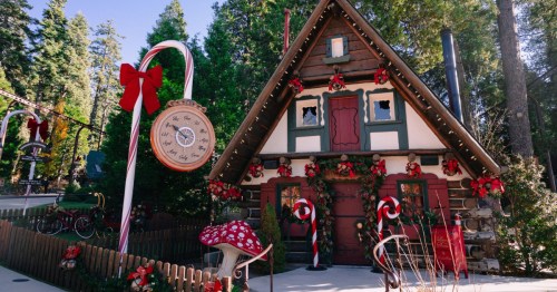 The exterior of a Christmas cottage with a candy cane clock outside the front door.