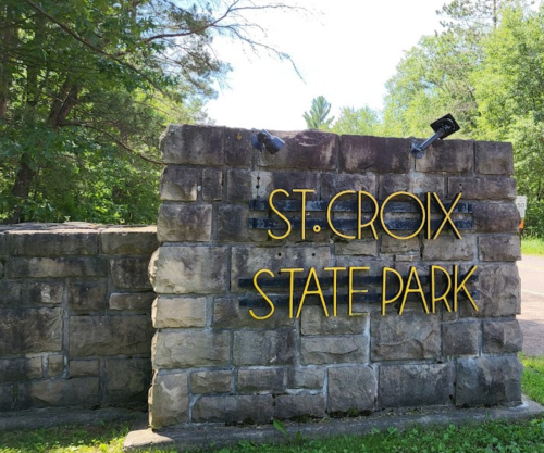 Sign for St. Croix State Park made of stone, surrounded by trees and greenery.