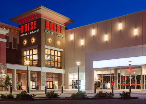 Exterior of Boise Towne Square shopping mall at night, featuring bright signage and storefronts.
