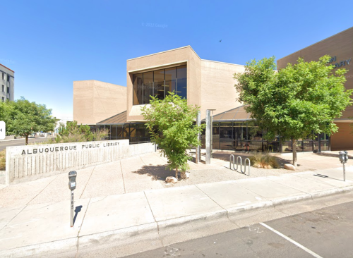 Exterior view of Albuquerque Public Library, featuring modern architecture and greenery under a clear blue sky.