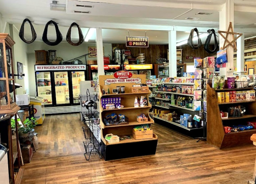 A cozy store interior featuring shelves of products, a refrigerated section, and rustic decor elements.