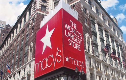 Macy's storefront with a large sign reading "The World's Largest Store" against a blue sky.