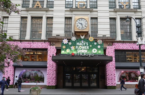 Macy's storefront adorned with pink flowers for the Flower Show, featuring a green sign and decorative elements.