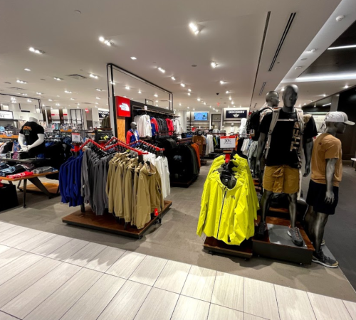 A retail store display featuring clothing racks and mannequins showcasing various apparel in a well-lit space.