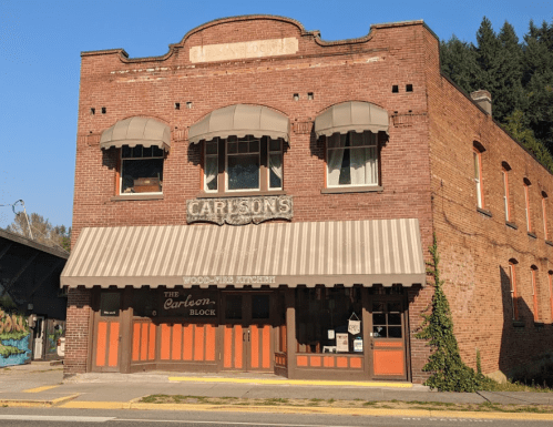 Historic brick building with large windows, awnings, and a sign reading "Carlson's" and "The Carbon Block."