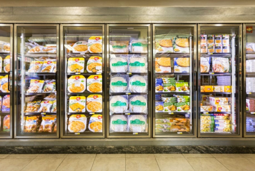 Frozen food aisle with various packaged meals and snacks displayed in glass-fronted freezers.