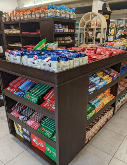A wooden display table filled with various snack packages, including chips and cookies, in a store setting.