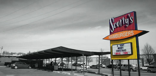 A black-and-white image of Scott's Hamburgers with a colorful sign and a festive message for Christmas.