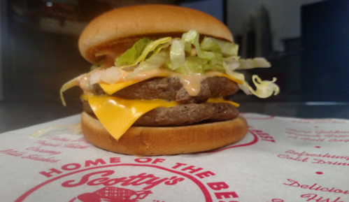A double cheeseburger with lettuce, cheese, and special sauce on a toasted bun, served on branded paper.