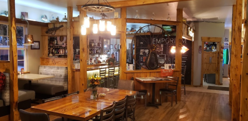 Cozy restaurant interior with wooden decor, a bar area, and a bicycle hanging on the wall. Warm lighting and seating.