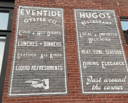 Vintage wall sign for Eventide Oyster Co. and Hugo's Restaurant, listing menu items and dining options.