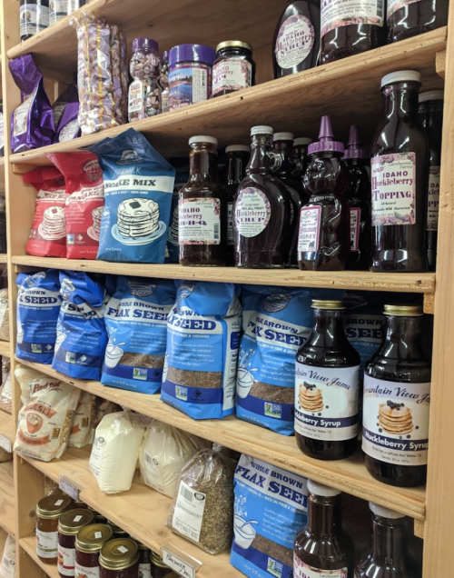Shelves filled with various food products, including syrups, pancake mix, and flax seeds in colorful packaging.