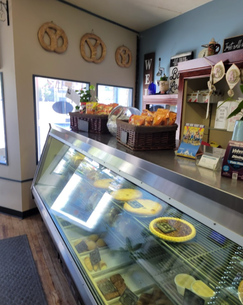 A display case filled with various food items, with baskets of snacks and a cozy interior in a small shop.