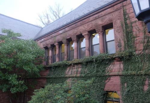 Historic building with ornate stonework, featuring arched windows and ivy climbing the walls.