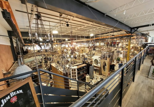 A spacious store filled with various lighting fixtures and home decor items, viewed from an upper level.