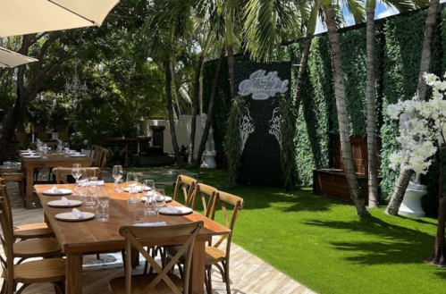 Outdoor dining area with wooden tables, lush greenery, and decorative elements, creating a serene atmosphere.