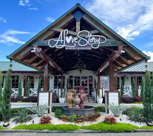 Exterior of A Love Story Winery & Bistro, featuring a charming entrance with sculptures and lush landscaping.