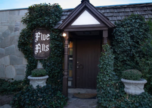 Entrance to "Five Hills" restaurant, featuring a wooden door surrounded by ivy and decorative planters.