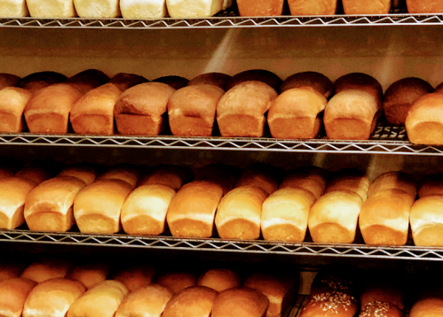 Freshly baked loaves of bread arranged neatly on wire racks in a bakery.