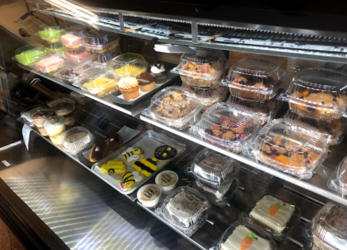 A display case filled with various desserts, including cupcakes, pastries, and decorated cookies.