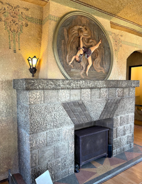 Artistic fireplace with a stone mantel, featuring a decorative relief above and intricate wall designs.