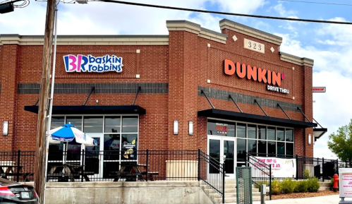 Exterior of a Dunkin' and Baskin-Robbins store, featuring a drive-thru and outdoor seating area.