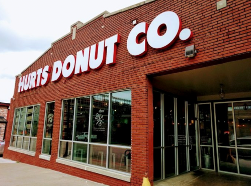 Exterior of Hurts Donut Co. featuring a red brick facade and large white lettering.