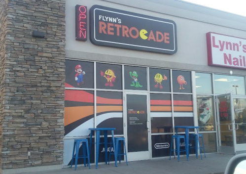 Exterior of Flynn's Retrocade featuring colorful arcade characters and a welcoming "Open" sign.