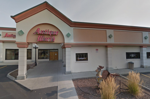 Exterior of an antique store with a sign reading "Antique World," featuring a decorative entrance and landscaping.