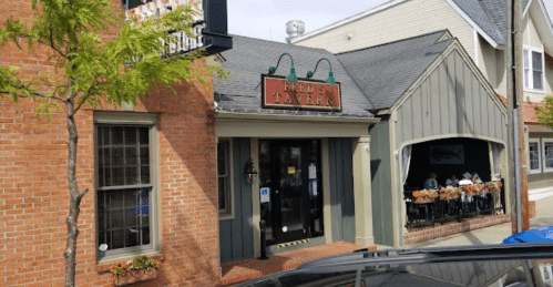 Exterior of Fred's Tavern, featuring a brick facade and a green awning, with outdoor seating visible.