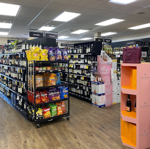 A well-organized store aisle featuring shelves of wine, snacks, and beverages in a bright, spacious environment.