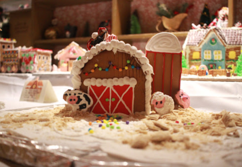 A festive gingerbread barn with candy decorations, surrounded by colorful sprinkles and small animal figures.
