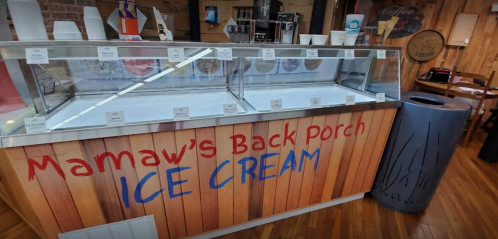 A colorful ice cream shop display with a sign reading "Mamaw's Back Porch Ice Cream" and empty ice cream tubs.