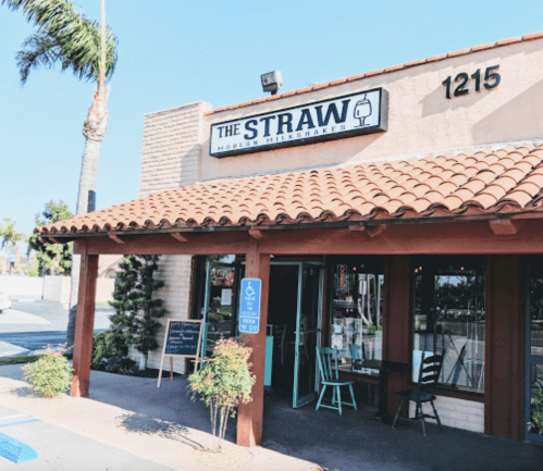 Exterior of "The Straw" modern milkshake shop, featuring a tiled roof and outdoor seating area.