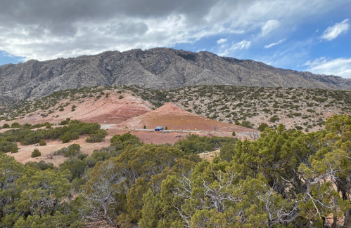A scenic view of mountains with rocky terrain and sparse vegetation under a partly cloudy sky.