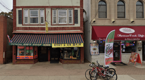 A street view of two shops: a gift shop with a striped awning and a Mexican restaurant with colorful signage.