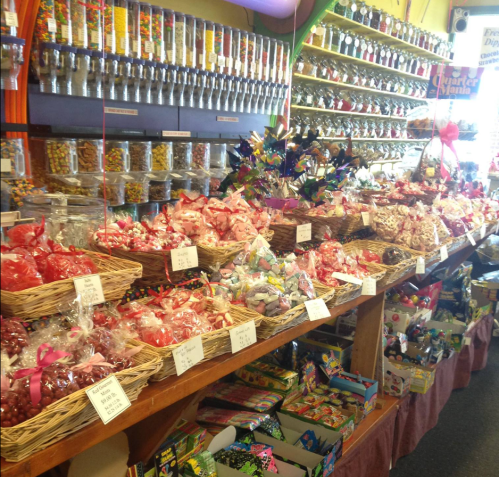 A colorful candy store display with jars, baskets of sweets, and various treats lining the shelves.