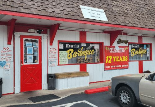 Exterior of Henri's Barbeque, featuring red and white decor, a welcoming entrance, and a sign celebrating 12 years in business.