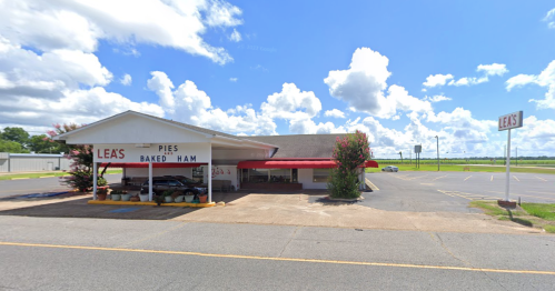 A roadside restaurant with a red awning, sign reading "Lea's Pies Baked Ham," and a clear blue sky in the background.