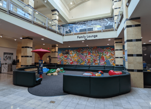A spacious family lounge with colorful seating, a vibrant mural, and play areas for children.