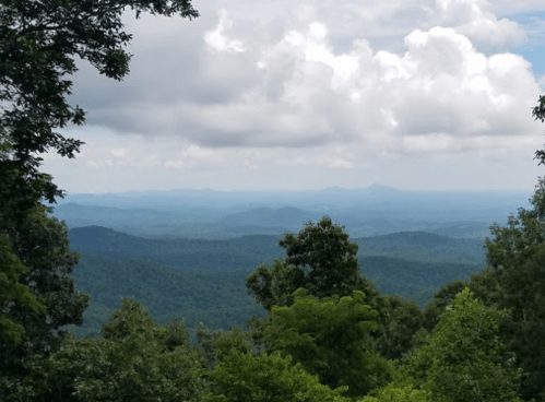 A panoramic view of rolling green mountains under a cloudy sky.