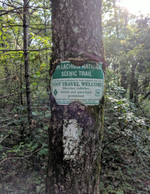 Sign on a tree indicating the Appalachian National Scenic Trail, welcoming foot travel and prohibiting vehicles and bicycles.